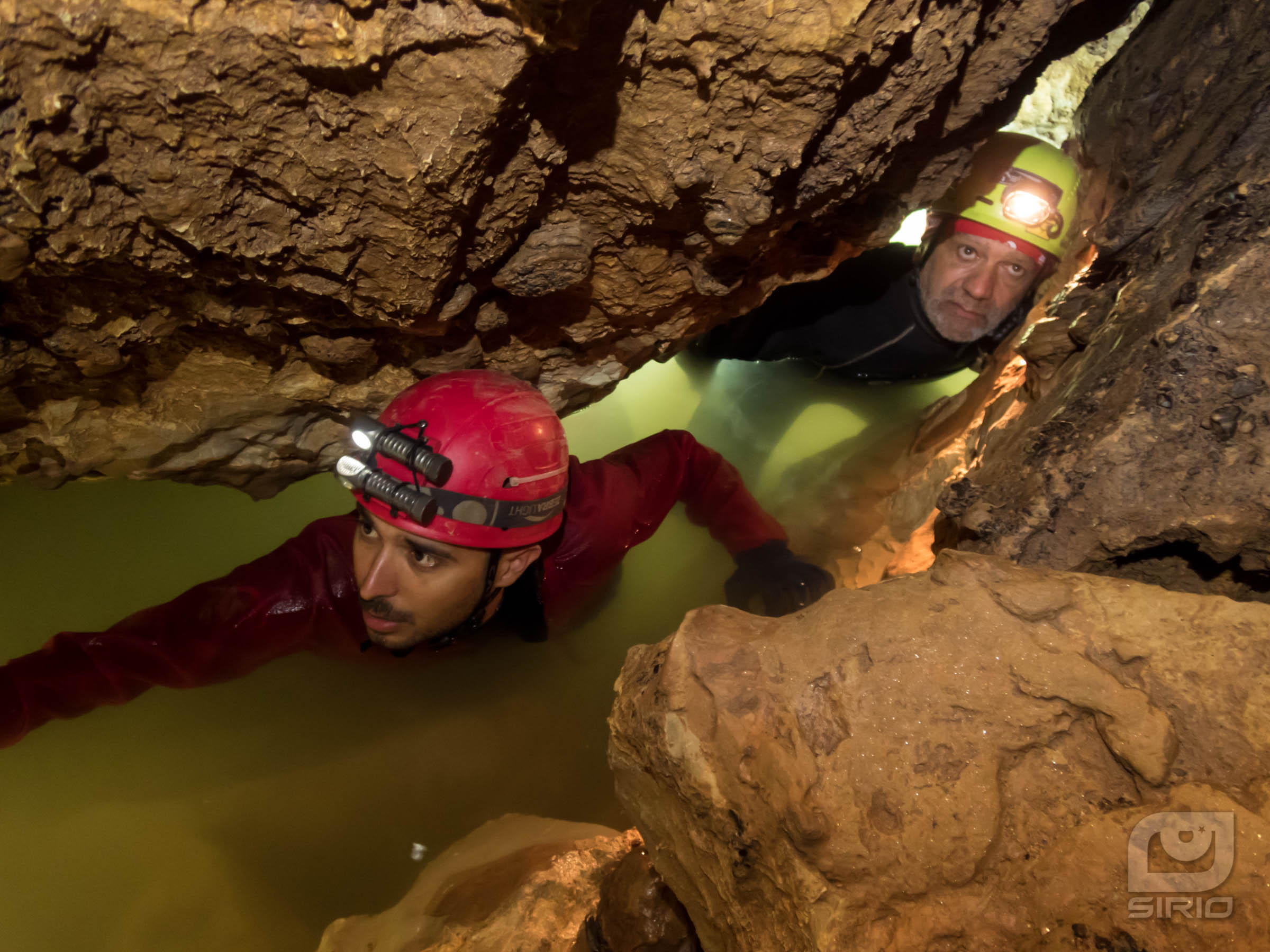 caver crawling into the water
